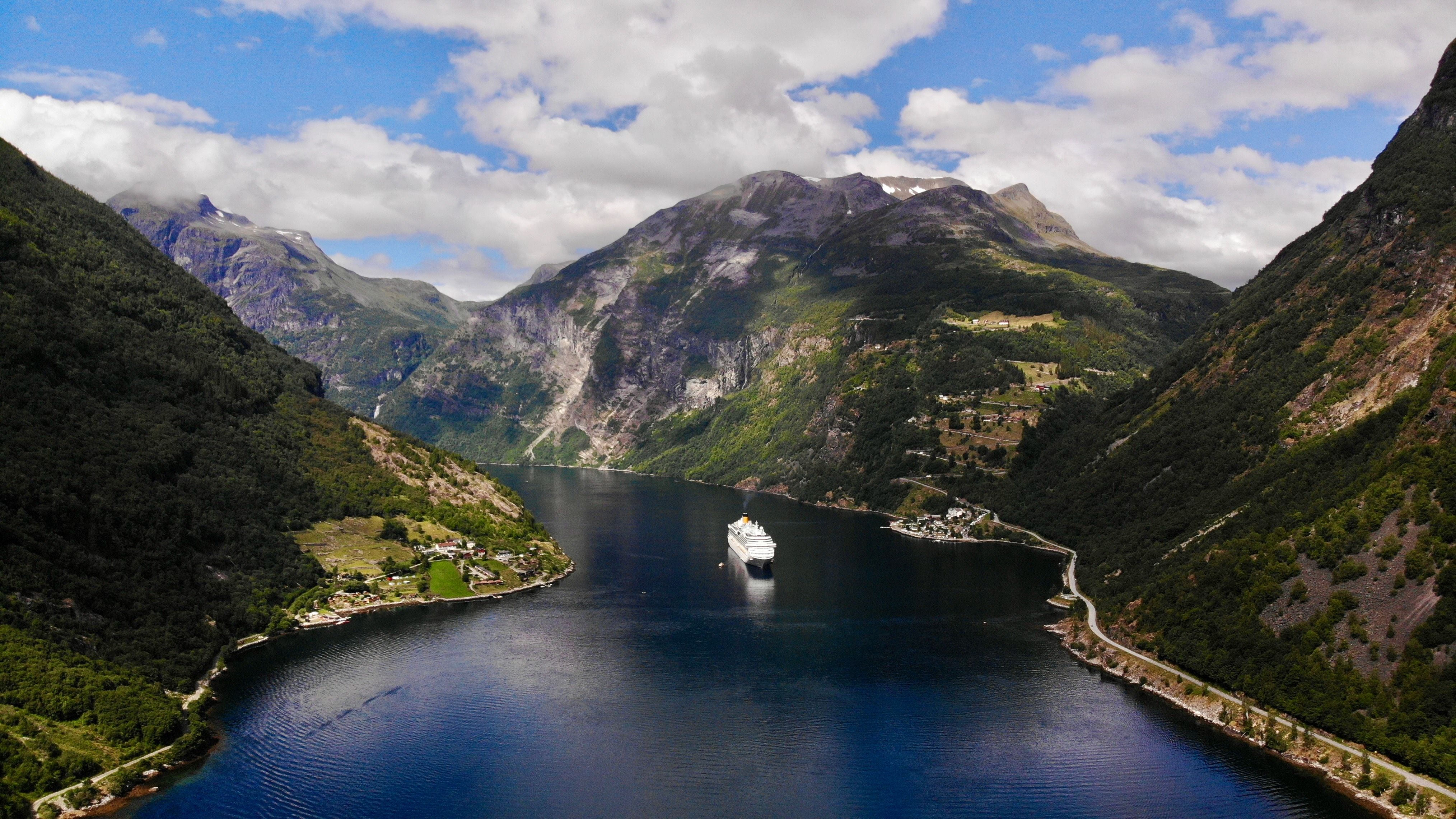 Kreuzfahrtschiff im Geirangerfjord in Norwegen umgeben von hohen Bergen und Fjordlandschaft