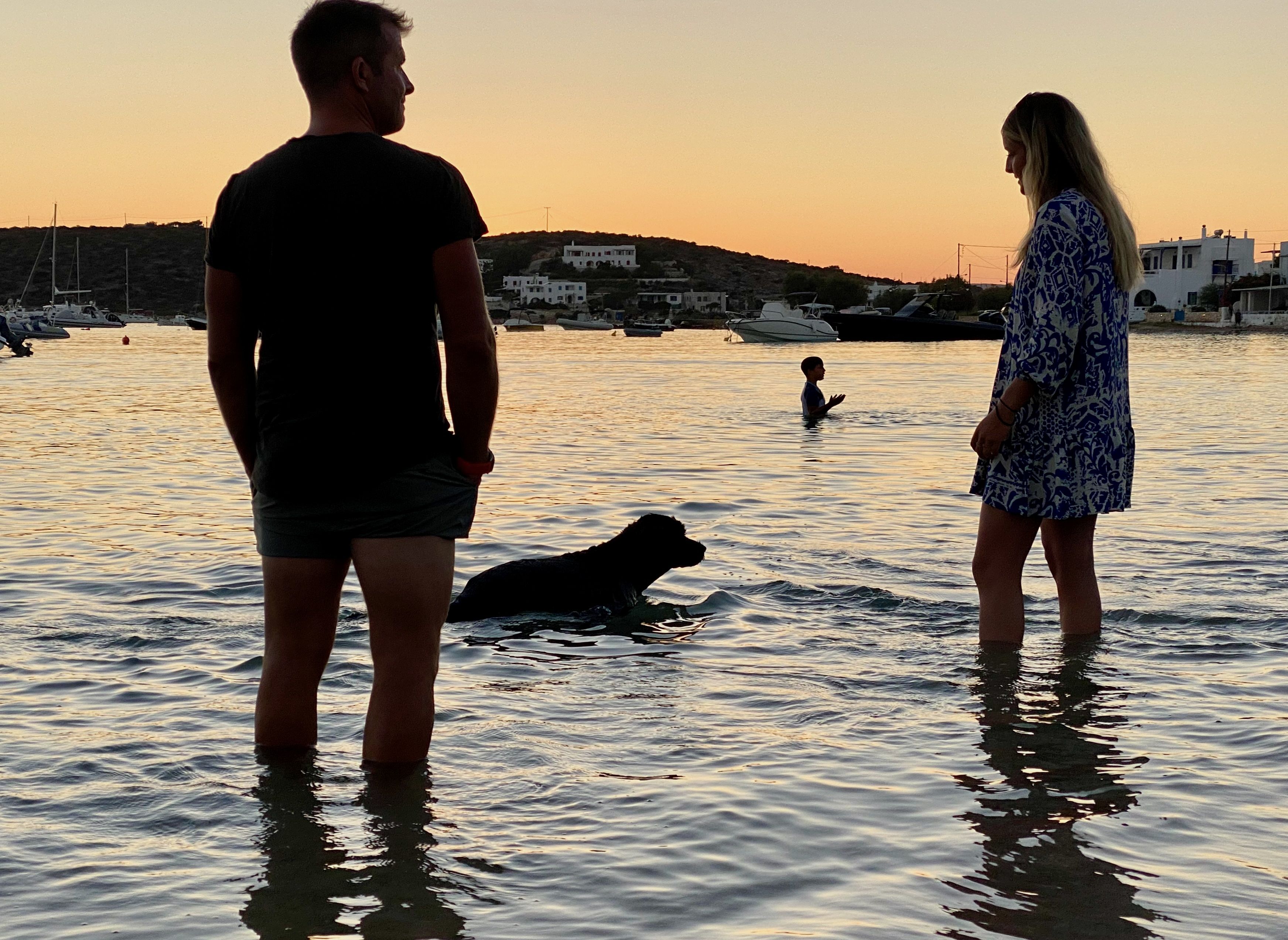 Zwei Teilnehmer der Hundekreuzfahrt am Strand mit Hund bei Sonnenuntergang
